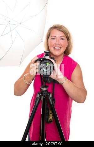 Portrait vertical d'un photographe utilisant un appareil photo reflex numérique sur un trépied et une lumière pour prendre des photos en studio. Banque D'Images