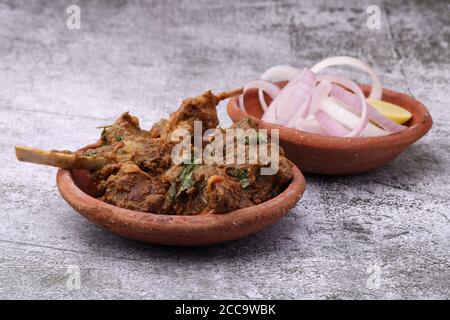 Bhuna Gosht mutton masala OU curry d'agneau indien servi avec oignon dans un bol de terre sur fond moody Banque D'Images