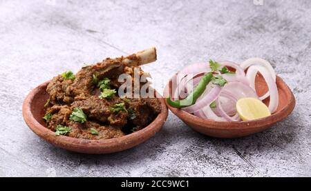 Bhuna Gosht mutton masala OU curry d'agneau indien servi avec oignon dans un bol de terre sur fond moody Banque D'Images