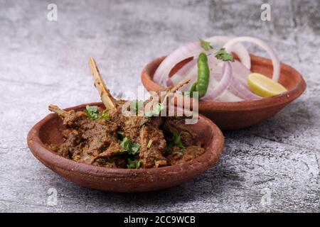 Bhuna Gosht mutton masala OU curry d'agneau indien servi avec oignon dans un bol de terre sur fond moody Banque D'Images