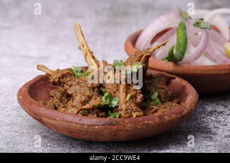 Bhuna Gosht mutton masala OU curry d'agneau indien servi avec oignon dans un bol de terre sur fond moody Banque D'Images