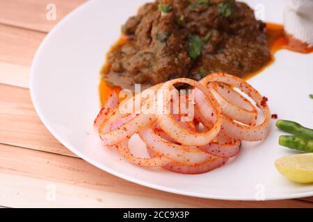 Curry de mouton servi avec des oignons sur fond de bois. Banque D'Images