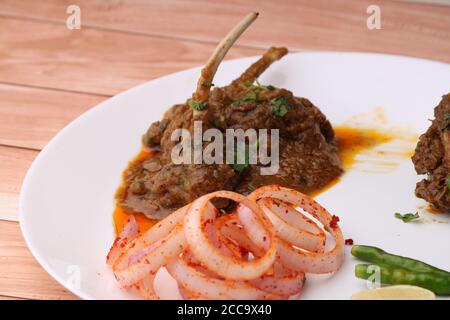 Curry de mouton servi avec des oignons sur fond de bois. Banque D'Images