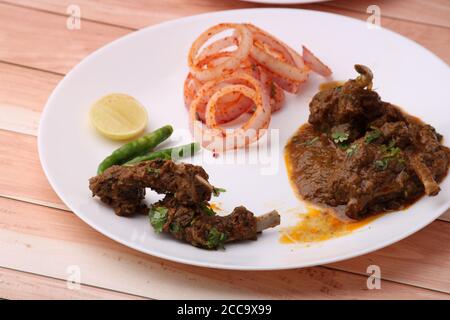 Curry de mouton servi avec des oignons sur fond de bois. Banque D'Images