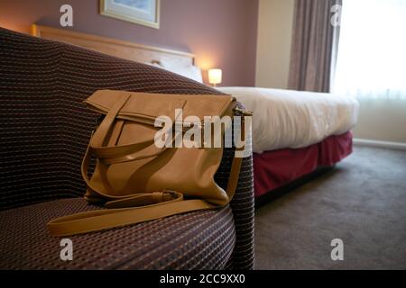 Photographie d'un sac à main sur une chaise dans une chambre d'hôtel. Banque D'Images