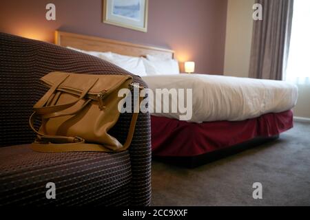 Photographie d'un sac à main sur une chaise dans une chambre d'hôtel. Banque D'Images