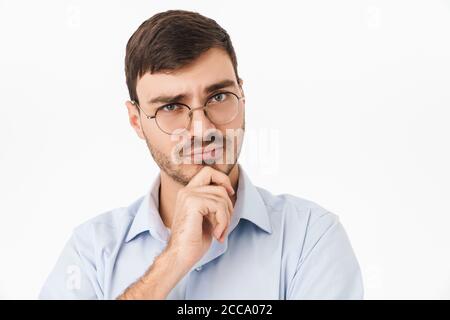 Photo gros plan de penser jeune homme dans les lunettes posant et regarder la caméra isolée sur fond jaune Banque D'Images