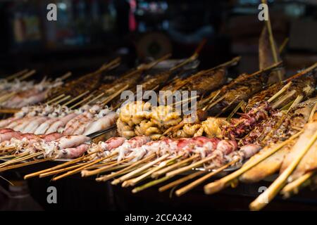 Poisson frais sur barbecue dans un marché de rue en Asie. Différents types de poissons et de bord de mer. Poissons, calmars et pieuvre. Tous sont grillés. Banque D'Images