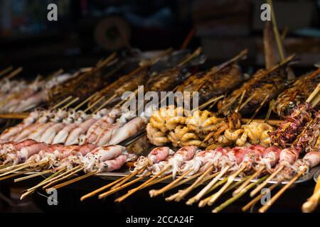 Poisson frais sur barbecue dans un marché de rue en Asie. Différents types de poissons et de bord de mer. Poissons, calmars et pieuvre. Tous sont grillés. Banque D'Images