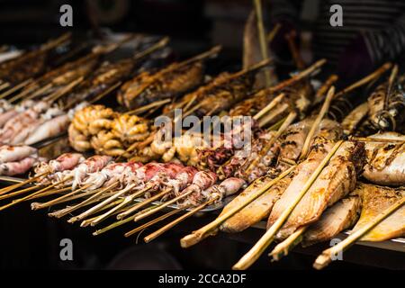 Poisson frais sur barbecue dans un marché de rue en Asie. Différents types de poissons et de bord de mer. Poissons, calmars et pieuvre. Tous sont grillés. Banque D'Images