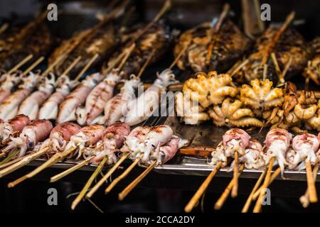 Poisson frais sur barbecue dans un marché de rue en Asie. Différents types de poissons et de bord de mer. Poissons, calmars et pieuvre. Tous sont grillés. Banque D'Images