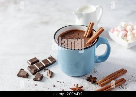 Chocolat chaud épicé à la cannelle et anis étoilé dans un mug bleu émaillé sur fond blanc. Boisson chaude et confortable pour l'automne ou l'hiver. Banque D'Images