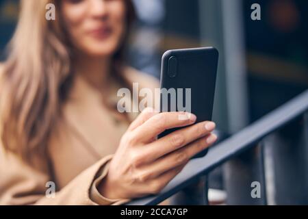 Femme blonde dans une veste en utilisant son gadget Banque D'Images