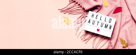 Visionneuse avec texte Hello Autumn, écharpe confortable et feuilles sur bannière pastel. Banque D'Images