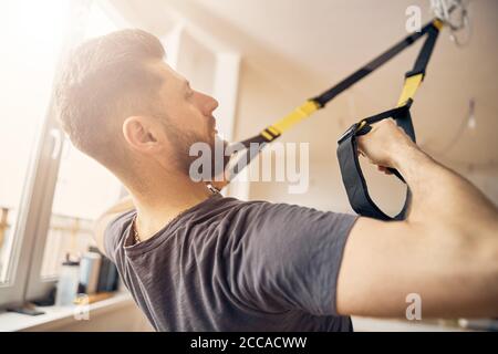 Homme sportif faisant un exercice de rangée TRX Banque D'Images