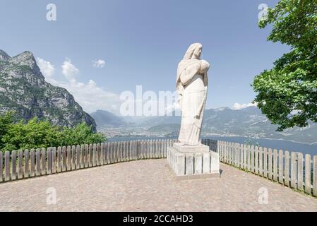 La statue de la Madonna Regina Mundi devant le panorama des montagnes et des falaises et la rive nord du lac de Garde, Trentin, Italie Banque D'Images