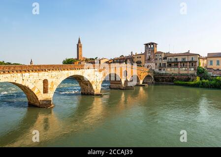 Le pont romain Ponte Pietra en pierre sur la rivière Adige dans la vieille ville de Vérone est éclairé le soir au soleil, Vénétie, Italie Banque D'Images