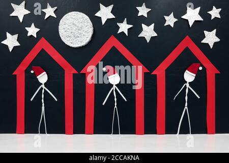 Trois hommes de bâton figure portant le chapeau de santa seul à l'intérieur d'une maison rouge. Concept d'isolement et de séjour à la maison pendant les fêtes de Noël. Banque D'Images