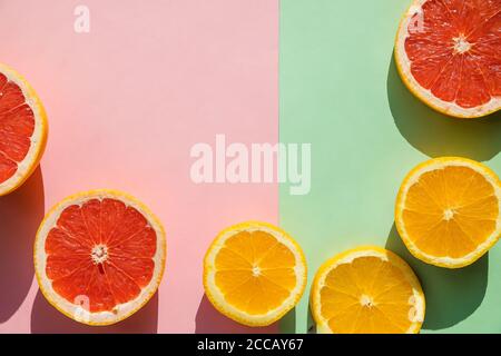 Fond créatif composé de fruits tropicaux d'été, de pamplemousse, d'orange, de mandarine sur fond rose pastel et vert. Citrus Food concept. Pose à plat Banque D'Images