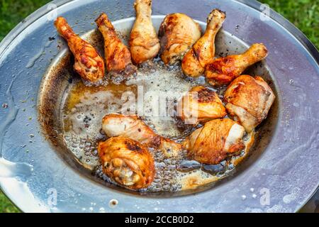 Faire frire le poulet dans une assiette à huile chaude. Cuisses de poulet rôties à la peau dorée croustillante et sélective. Banque D'Images