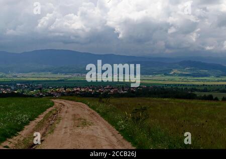 Scène d'été avec prairie, forêt, les villages bulgares Alino, Belchin près de l'ancien village Tsari Mali Grad et les montagnes Rila et Verila Banque D'Images