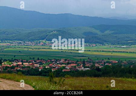 Scène d'été avec prairie, forêt, les villages bulgares Alino, Belchin près de l'ancien village Tsari Mali Grad et les montagnes Rila et Verila Banque D'Images