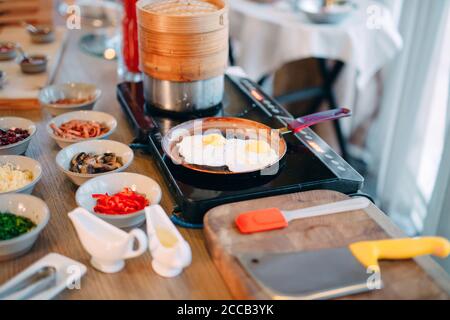 Le petit-déjeuner. Les œufs brouillés sont cuits sur une plaque à induction au restaurant. Banque D'Images