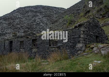 Ancienne maison d'ardoise par une montagne d'ardoise dans le Hautes terres britanniques Banque D'Images