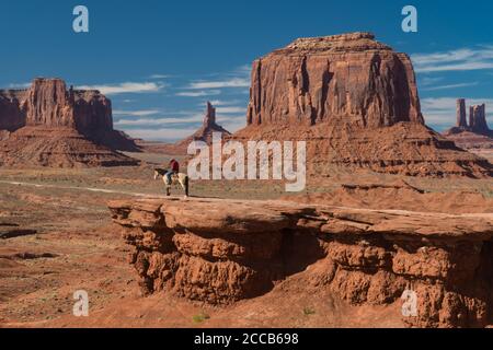 Un homme Navajo pose sur un cheval sur une corniche dans Monument Valley, Utah, États-Unis Banque D'Images