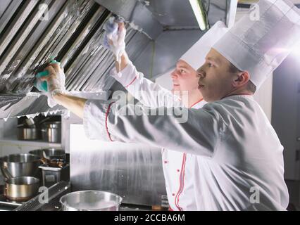 Jour sanitaire dans le restaurant. Lavez vos répétitions de travail. Laver cuisine four, cuisinière et hotte dans le restaurant. Banque D'Images