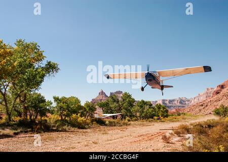 Un avion expérimental prend son envol de la piste d'atterrissage distante de Mexican Mountain sur la houle de San Rafael dans l'Utah. Un Cessna 185 Skywagon est garé par le Banque D'Images