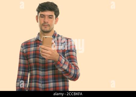 Studio shot of young man using mobile phone persan Banque D'Images