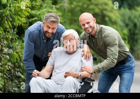 Grand-père handicapé en fauteuil roulant avec famille de soins Banque D'Images