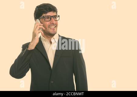 Young happy Persian businessman smiling while talking on mobile phone Banque D'Images