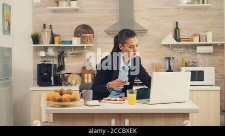 Femme d'affaires effectuant le paiement en ligne par carte de crédit sur un ordinateur portable pendant le petit déjeuner. Acheter en ligne des biens et des vêtements, en utilisant la technologie moderne dans la vie quotidienne, faire des paiements par Internet Banque D'Images