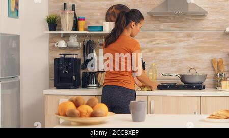 Femme prenant des œufs du réfrigérateur pour faire cuire le petit déjeuner. . La femme de ménage reçoit des œufs et d'autres ingrédients du réfrigérateur dans sa cuisine. Banque D'Images