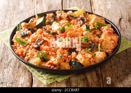 Riz au poulet, courgettes et champignons, tomates, fines herbes dans une poêle à frire sur la table. Horizontal Banque D'Images