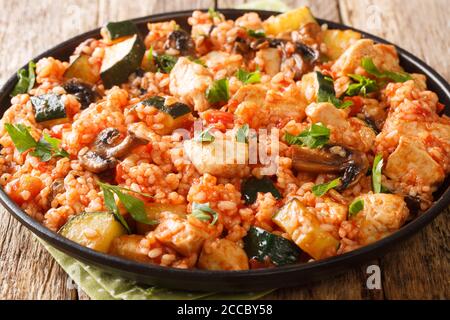 Riz délicieux avec poulet, courgettes et champignons, tomates, fines herbes dans une poêle à frire sur la table. Horizontal Banque D'Images