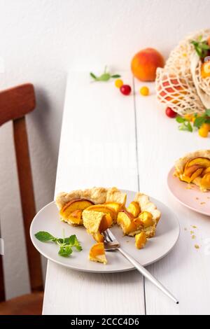 Délicieux morceau de tarte de pâte à croûte courte avec pêche sur une assiette avec une fourchette, cuit dans le four pêche clafoutis Banque D'Images