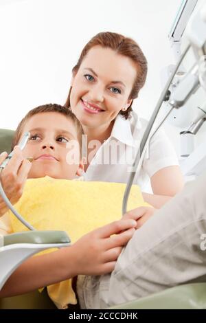 Assistant dentaire souriant et enfant assis sur la chaise chez le dentiste Banque D'Images