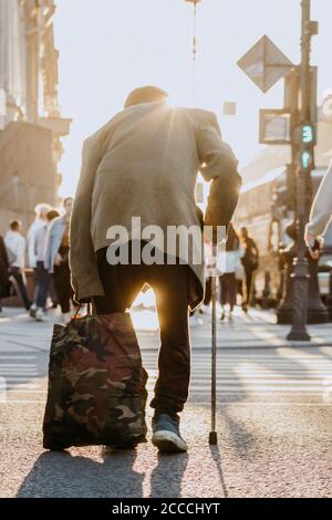 un vieux garçon avec bâton traverse la route du coucher du soleil la vie Banque D'Images