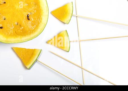 Morceaux de pastèque jaune sur bâtons. Plaque sur une surface blanche. Banque D'Images