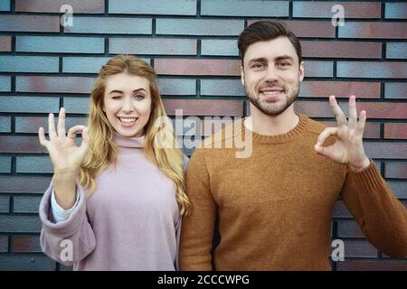 Gracieux gai positif jeune femme et homme ont des expressions satisfaites, garder les deux mains sur le coeur, se sentent reconnaissants aux invités, étant dans l'esprit élevé, St Banque D'Images