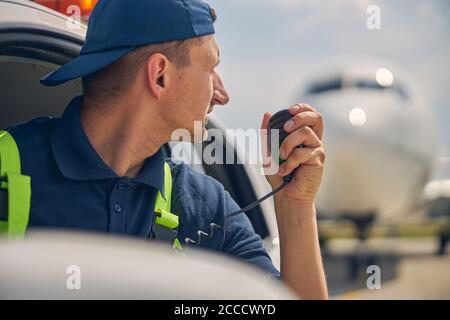 Chauffeur de voiture à l'aéroport utilisant une radio professionnelle Banque D'Images