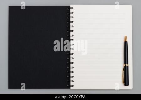 Espace de copie professionnel, ordinateur portable spirale de luxe avec couverture noire et stylo noir, vue de dessus Banque D'Images