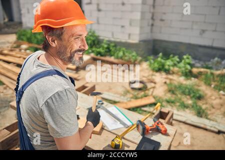Menuisier souriant avec un outil debout à l'extérieur Banque D'Images