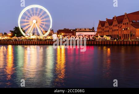 Gdansk, nord de la Pologne: Vue de nuit grand angle de la roue de ferris en mouvement et du centre-ville avec le signe de Gdansk et réflexion sur l'embouchure de la rivière Motława ne Banque D'Images