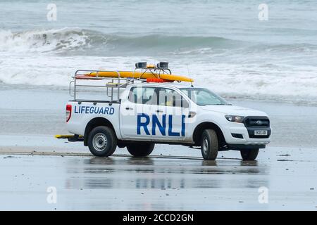 Portreath, Cornwall, Royaume-Uni. 21 août 2020. Météo Royaume-Uni. Un garde-nageur RNLI en patrouille sur la plage en gardant un œil sur les surfeurs et les boardeurs qui surfent sur les grandes vagues fouettées par Storm Ellen à Portreath, dans les Cornouailles, lors d'une journée de vents violents et de soleil brumeux. Crédit photo : Graham Hunt/Alamy Live News Banque D'Images