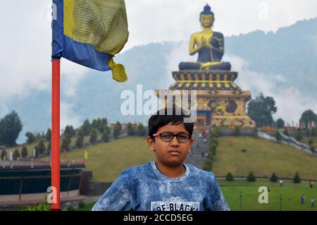 Un jeune garçon indien posant pour la photo devant la statue de Bouddha de Ravangla Parc de Sikkim, la focalisation sélective Banque D'Images