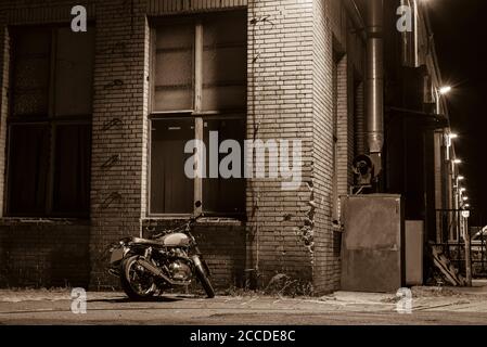 Une moto la nuit, une moto se tient sous une lumière de rue, un croiseur, une moto d'époque, une photo en noir et blanc Banque D'Images